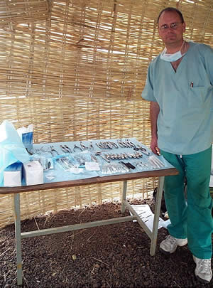 Dr. Doshier with a table of dental tools in dirt floored building